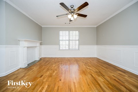 an empty living room with wood floors and a ceiling fan
