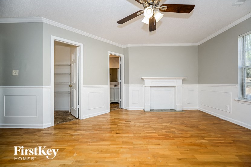 an empty living room with a ceiling fan and wood floors