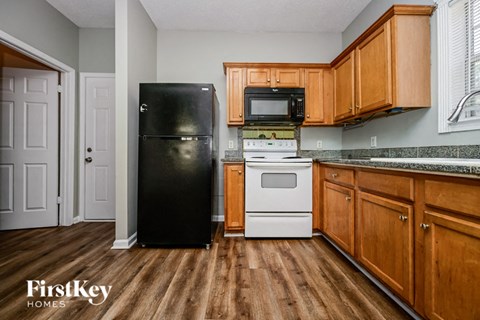 a kitchen with wooden cabinets and a black refrigerator