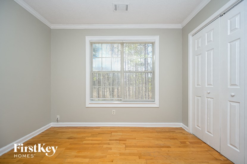 the second bedroom has a large window and hardwood floors