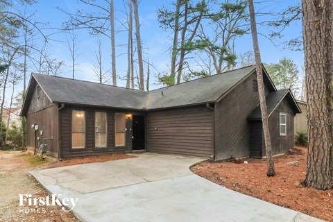 A house with a garage is surrounded by trees.