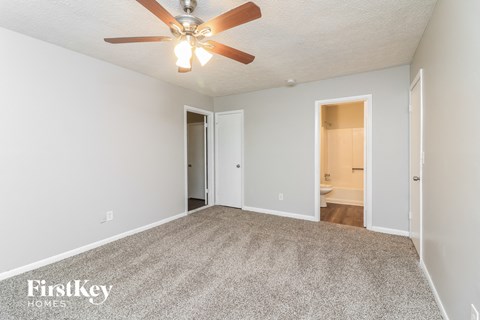 A spacious room with a ceiling fan and carpeted floor.