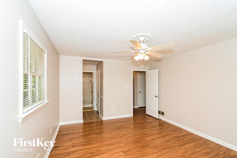 A spacious room with a ceiling fan and wooden flooring.