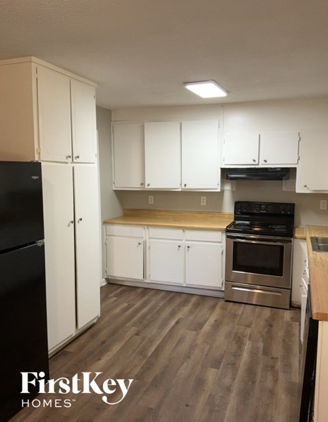 A kitchen with white cabinets and a black fridge.