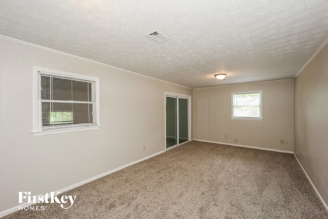 the living room of a home with carpet and a door to a closet