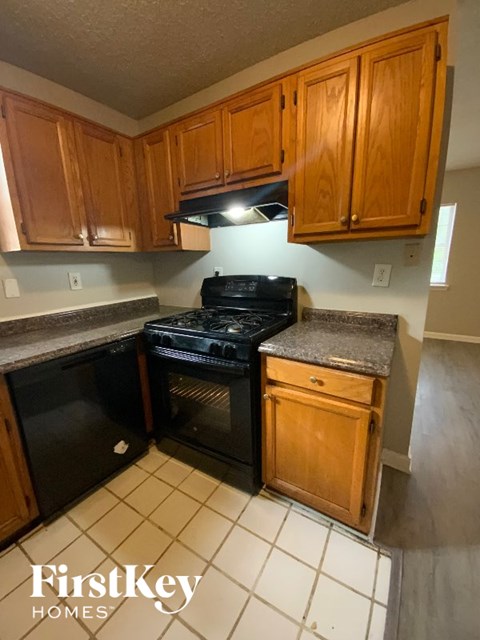 A kitchen with wooden cabinets and a black stove top oven.