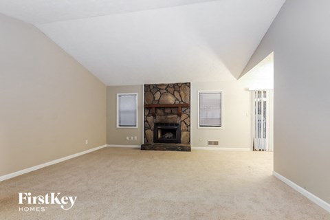 A spacious room with a fireplace and two windows.