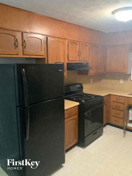 A black refrigerator and stove in a kitchen with wooden cabinets.