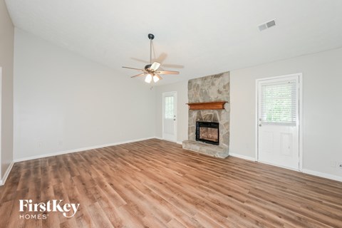 A spacious room with a fireplace and a ceiling fan.