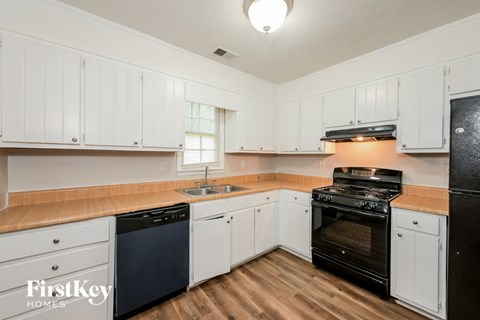 A kitchen with black appliances and white cabinets.