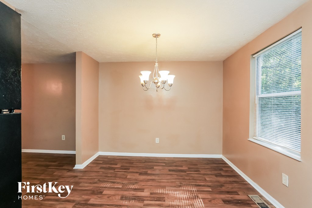 a empty dining room with a wood floor and two windows
