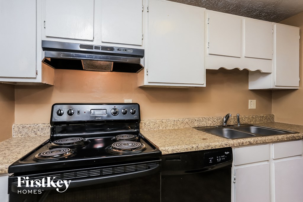 a kitchen with white cabinets and black appliances and a sink