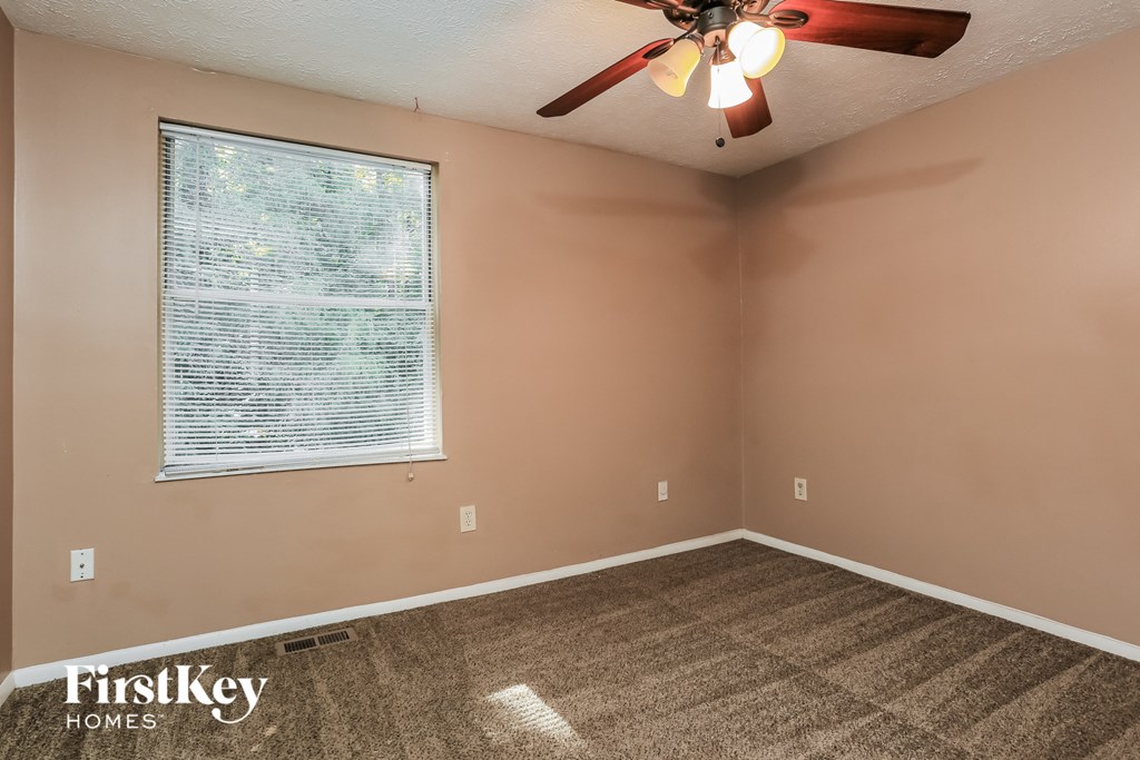 an empty bedroom with a ceiling fan and a window
