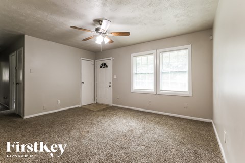 A room with a carpeted floor and a ceiling fan.