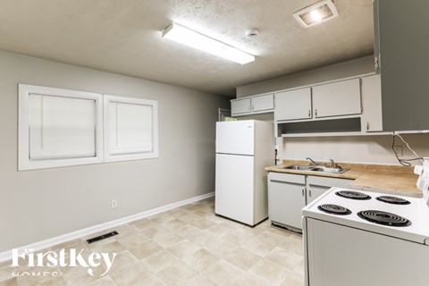 A kitchen with a stove, sink, and cabinets.