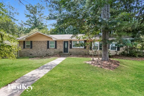 a small brick house with a tree in the front