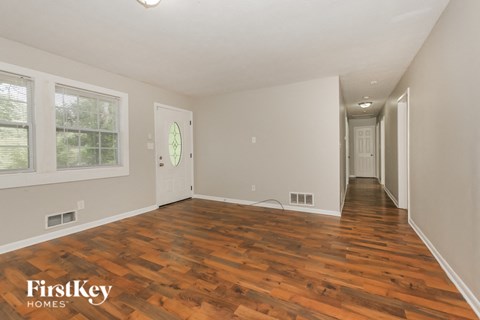 the living room and hallway of a house with wood floors