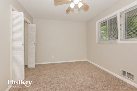 an empty bedroom with a ceiling fan and two windows