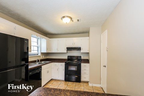 A kitchen with a black fridge and white cabinets.