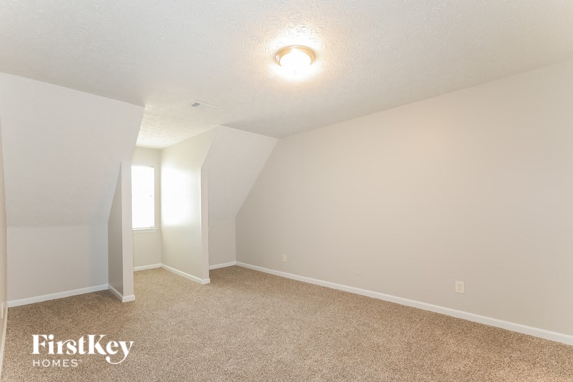 a bedroom with white walls and carpet and a window