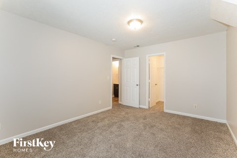 a spacious living room with carpet and white walls