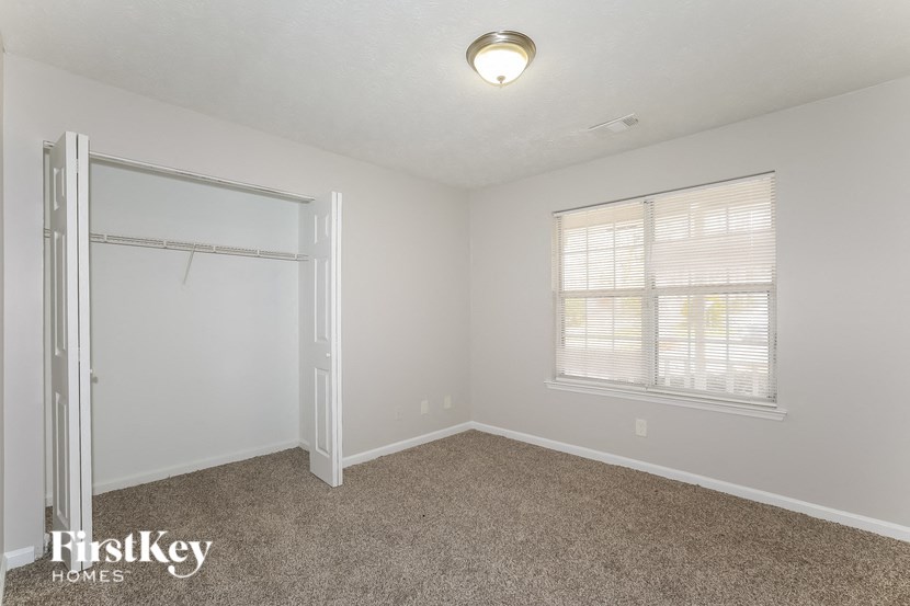 a bedroom with carpet and a closet and a window