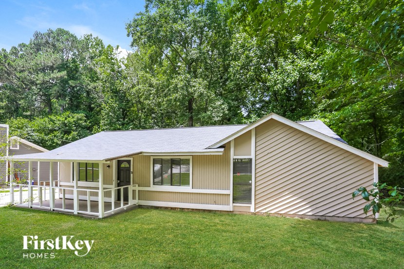 a small tan house with a porch and a lawn
