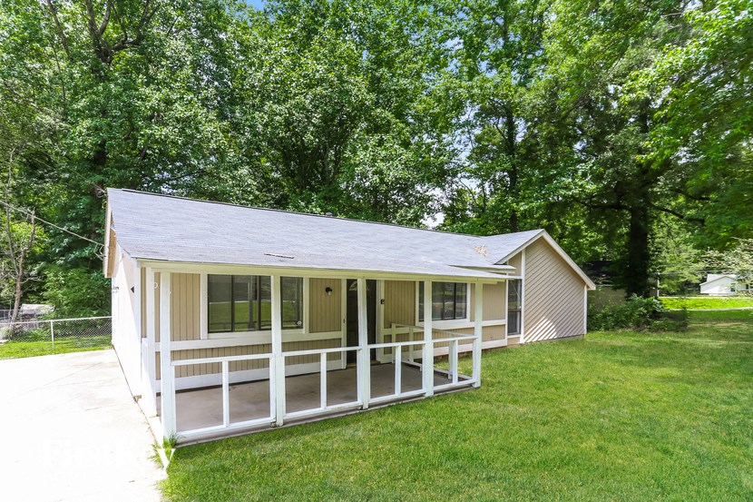 the cottage has a screened in porch and a lawn