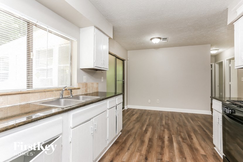 an empty kitchen with white cabinets and a large window