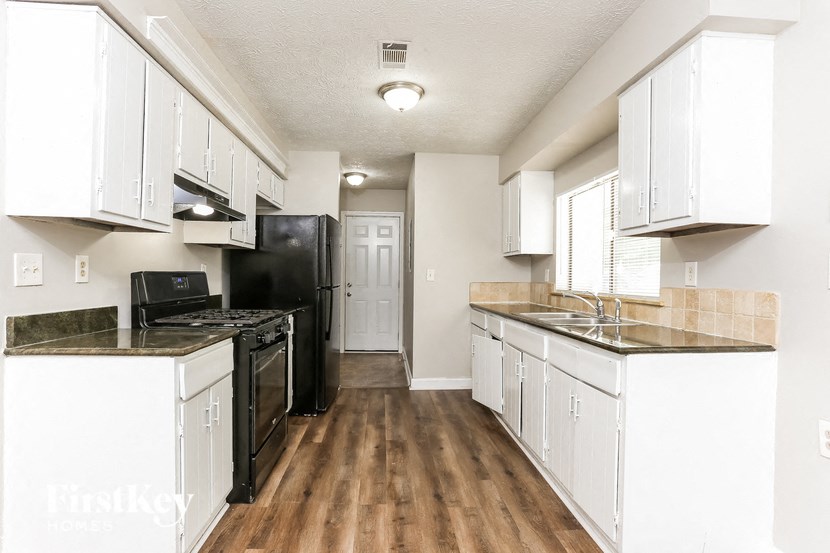 a kitchen with white cabinets and a black stove and refrigerator