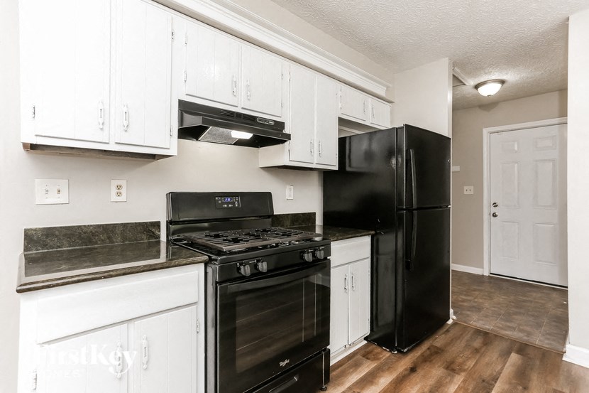 a kitchen with white cabinets and black appliances and a refrigerator