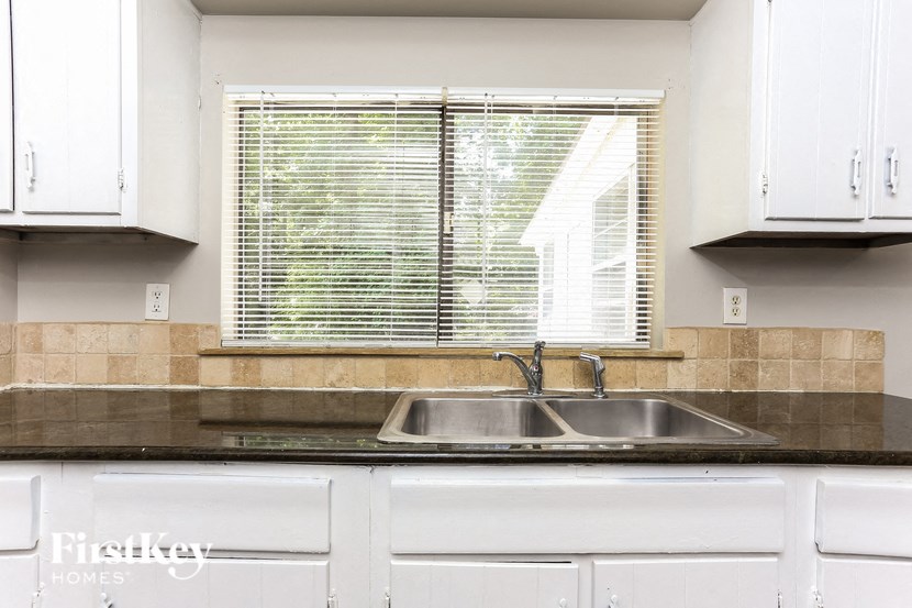 a kitchen with white cabinets and a sink and a window