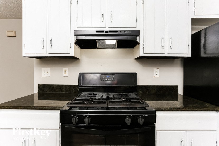 a kitchen with white cabinets and black stove and oven