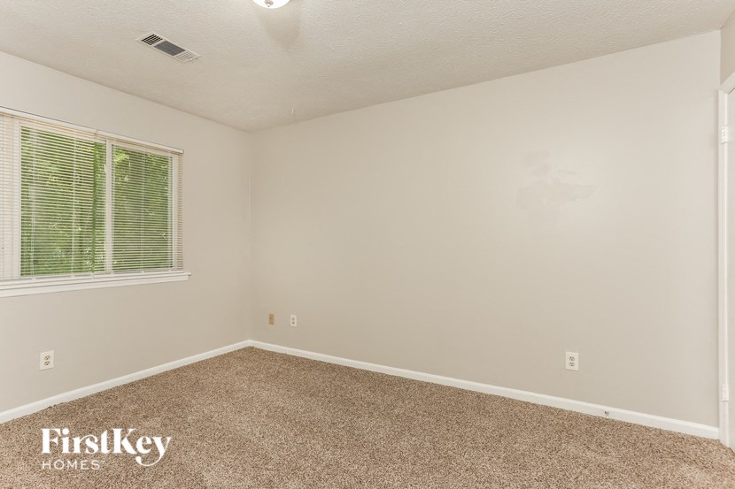 the upstairs bedroom has a carpeted floor and a large window