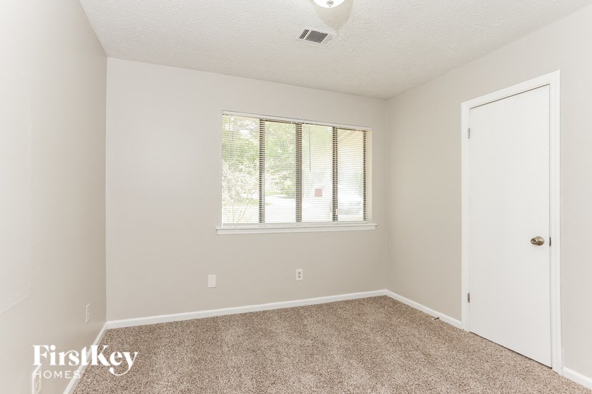 a bedroom with carpet and a window and a door