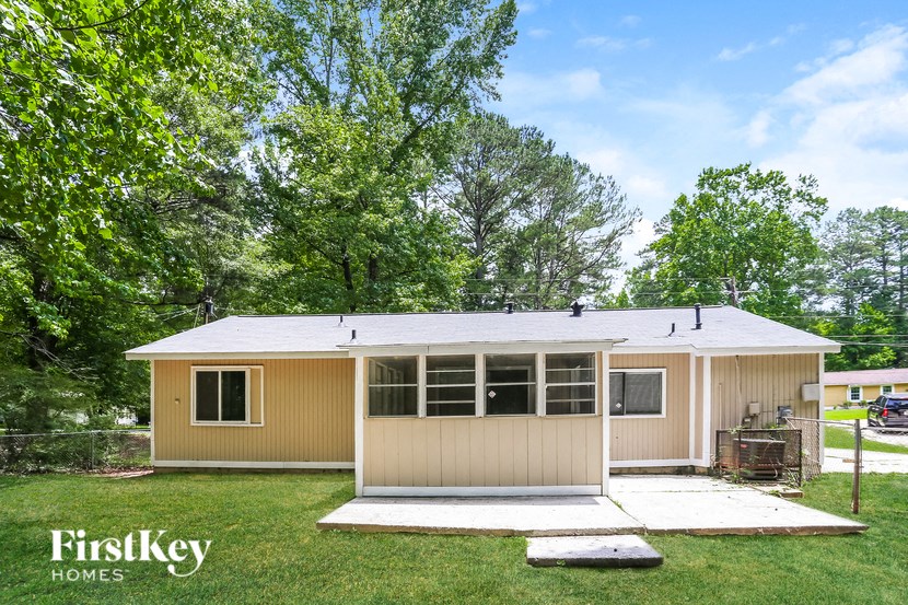 the exterior of a shed with a metal roof on a lawn with trees