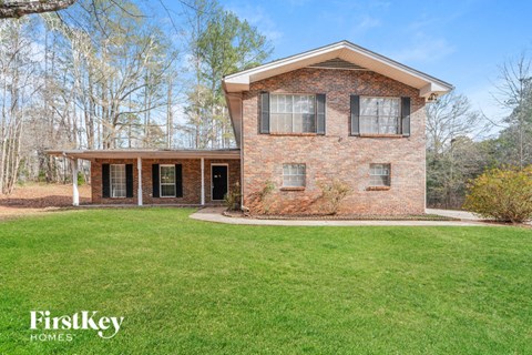 a small brick house with a green lawn and a porch