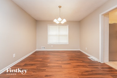 a empty dining room with wood flooring and a chandelier