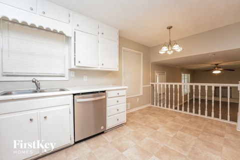 a kitchen with white cabinets and a dishwasher and a railing