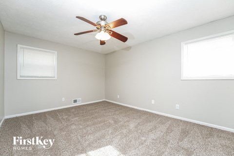 an empty room with a ceiling fan and two windows