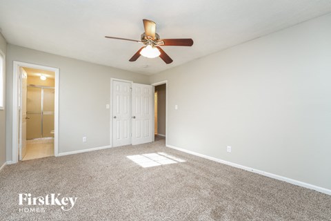 an empty living room with a ceiling fan and a door to a closet