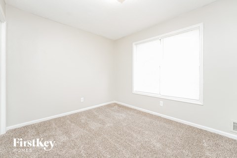 a bedroom with a carpeted floor and a window
