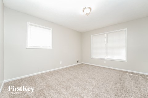 a bedroom with two windows and a carpeted floor