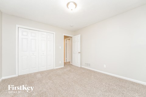 a spacious living room with carpet and a door to a closet