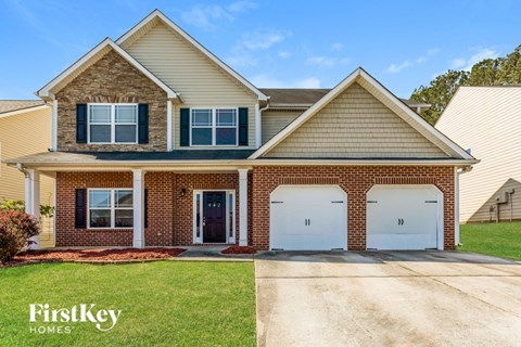 A two-story house with a garage and a brick wall.