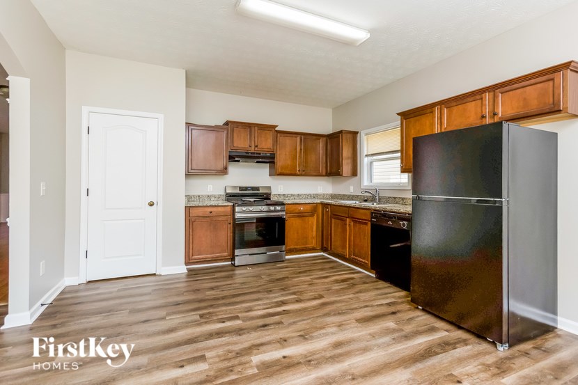 A kitchen with wooden cabinets and a black fridge.