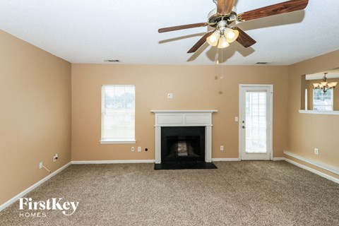 the living room has a fireplace and a ceiling fan