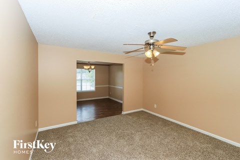 the spacious living room with ceiling fan and carpet