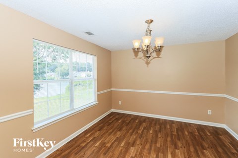 the dining room of a house with wood floors and a large window