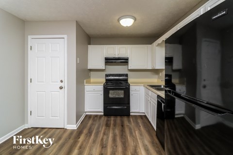 A kitchen with a black oven and white cabinets.